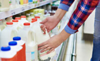 man picking up milk at the grocery store