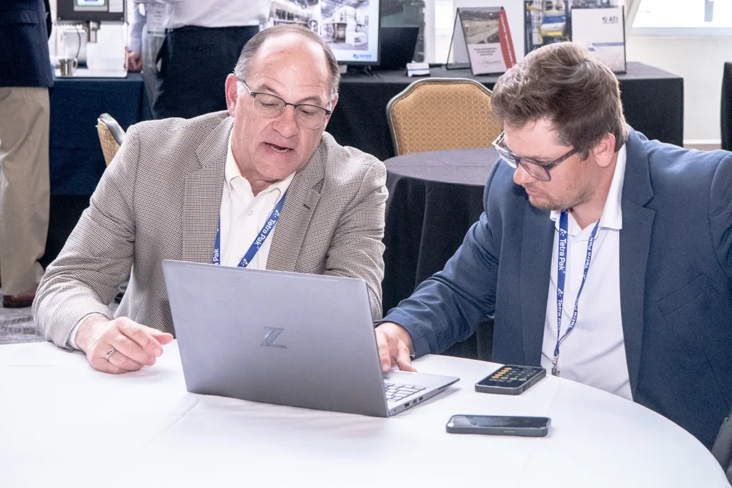 2 men watching a Membrane Technology Forum session on a laptop